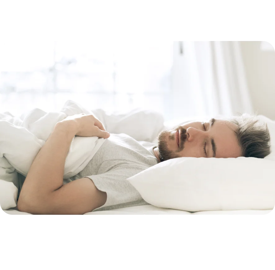 Relaxed young man sleeping on the pillow, on his back, in a white bedroom.